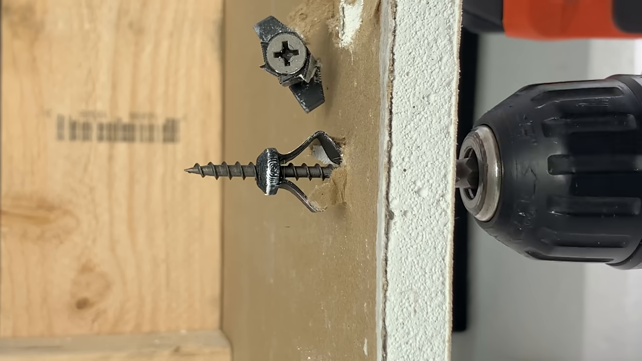 [03:20] A clear cutaway view of the final anchor design successfully buckling and clamping behind the drywall.